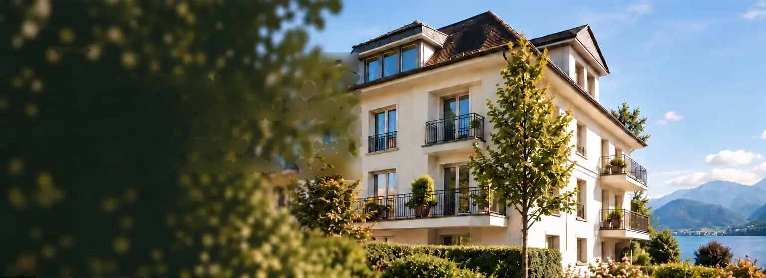 Gepflegtes Mehrfamilienhaus mit Balkonen und Blick auf See und Berge