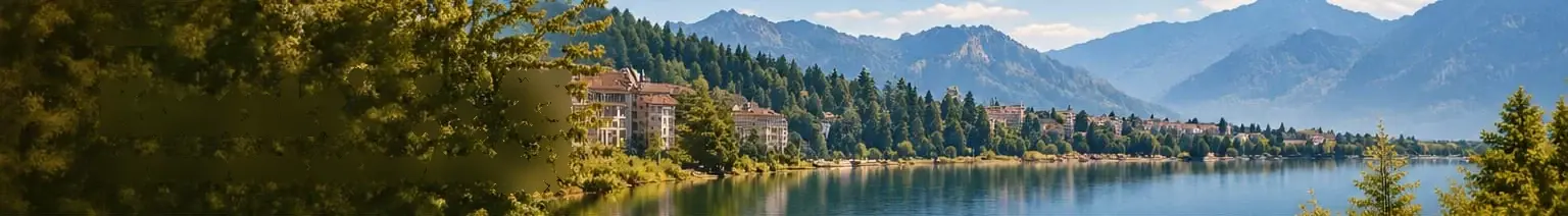 Blick über einen See auf bewaldete Hänge und Berge